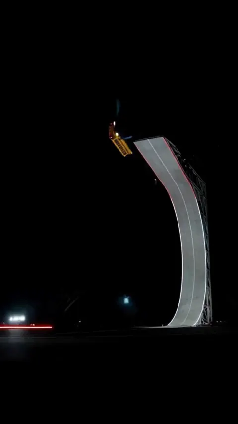 A stunt vehicle launching from a curved night ramp in the Roadster Ramp template